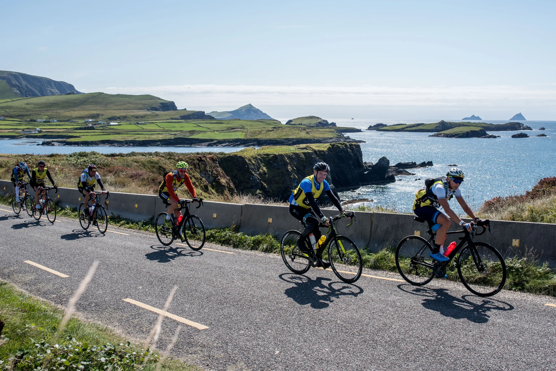 A group of cyclists on a supported coastal route